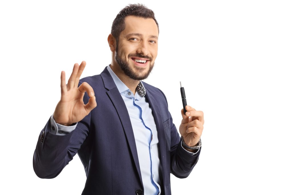 A man enjoying a heated tobacco stick while making the “ok” gesture