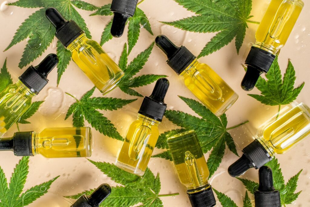 Botellas de aceite de CBD y hojas de cannabis dispersas